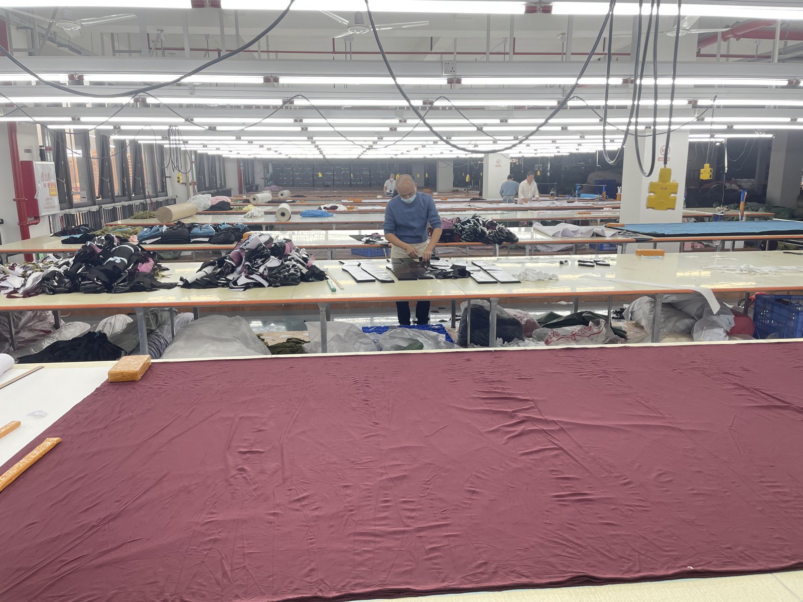 Fabric spread across a factory cutting table.